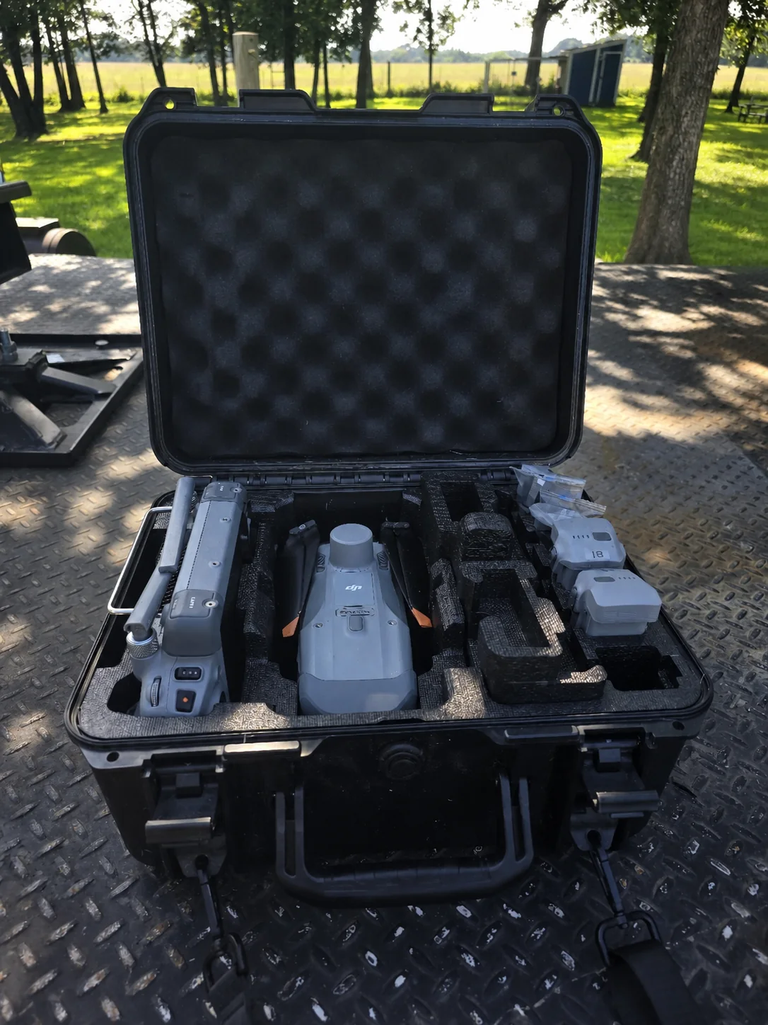 Open field case containing a DJI Matrice 4T aircraft, controller, and batteries on a diamond-plate trailer.