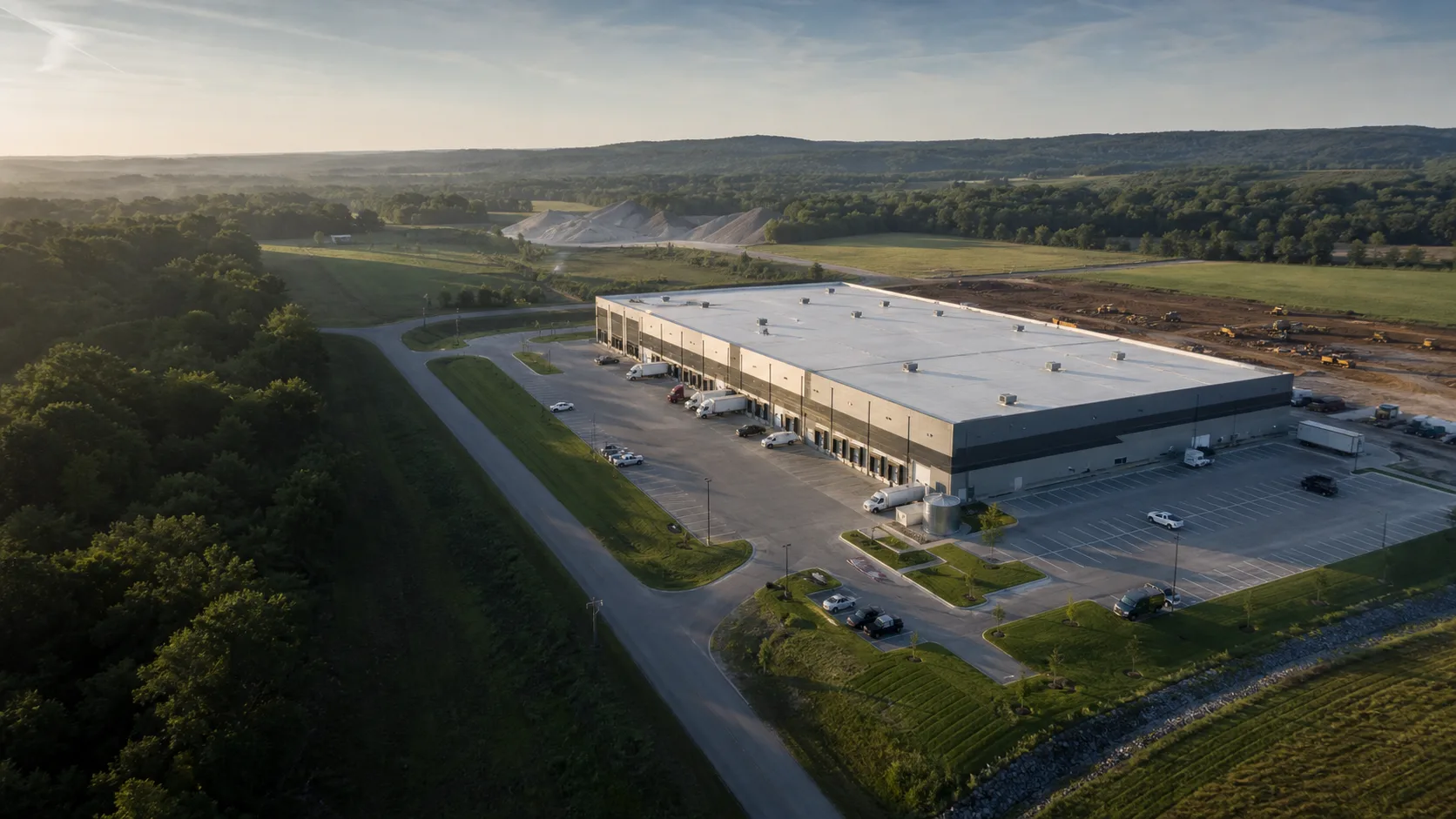 Illustrative aerial view of a coherent commercial warehouse property with roof, access, earthwork, and stockpile context in a Southwest Missouri landscape.