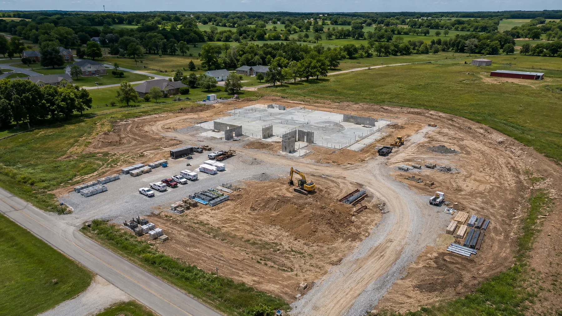 Aerial construction progress photo showing a Missouri jobsite with access routes, staging areas, materials, and visible structure progress.